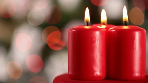 Three xmas candles burning in front of blurry xmas lights Stock Footage 81229145