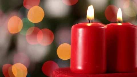 Three xmas candles spinning in front of blurry christmas tree Видео 80909230