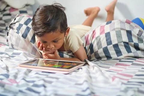 Three year old Asian boy at home bed using digital tablet computer Stock Photos