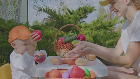 Three year old boy and his mother learning vegetables in home garden 1 Stock Footage 276894970