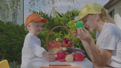 Three year old boy and his mother learning vegetables in home garden 3 Stock Footage 276898877
