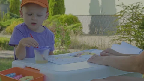 Three year old boy and his mother paintbrush in home garden 3 Stock Footage 276968560
