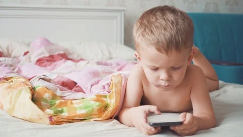 Three-year-old boy in bed is using a smartphone. 스톡 동영상 118766586