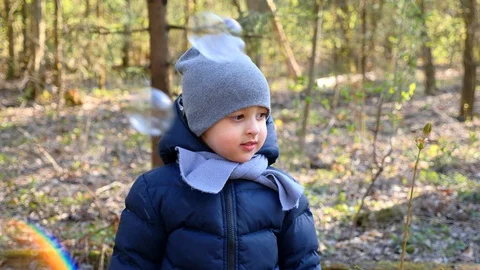Three year old boy in a blue jacket scarf and hat catches Stock Footage 129572960