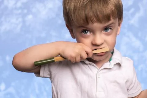A three year old boy brushes his teeth with a bamboo toothbrush Stock Photos