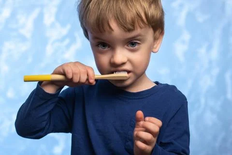 A three-year-old boy brushes his teeth with a bamboo toothbrush Stock Photos