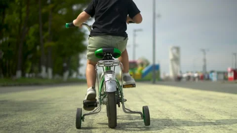 Three year old boy close up back view riding green kids bicycle in park Vídeos de archivo 331285109