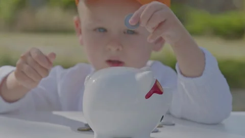 Three year old boy collect coins in piggy bank in home garden 3 Stock Footage 276939572