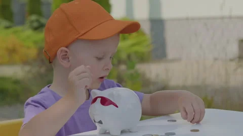 Three year old boy collect coins in piggy bank in home garden 2 Stock Footage 278052658