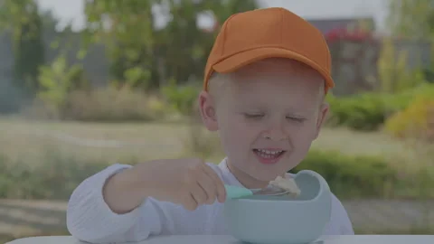 Three year old boy eating porridge in home garden 3 Stock Footage 276942182