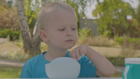 Three year old boy eating porridge in home garden 1 Stock Footage 276969461