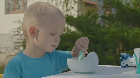 Three year old boy eating porridge in home garden 2 Stock Footage 278055364