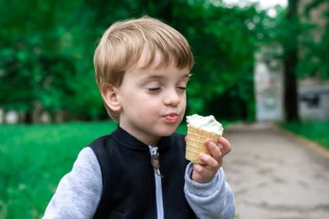 Three year old boy in the park eating ice cream with his eyes closed. Foto stock
