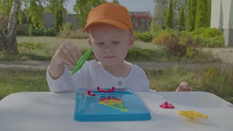 Three year old boy putting togeather a puzzle in home garden 3 Stock Footage 276941873