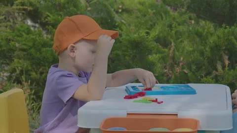 Three year old boy putting togeather a puzzle in home garden 2 Stock Footage 278105586
