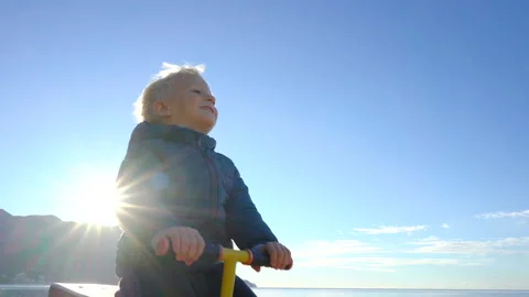 Three year old boy swinging on a swing in the sunny morning on the beach Stock Footage 99733561