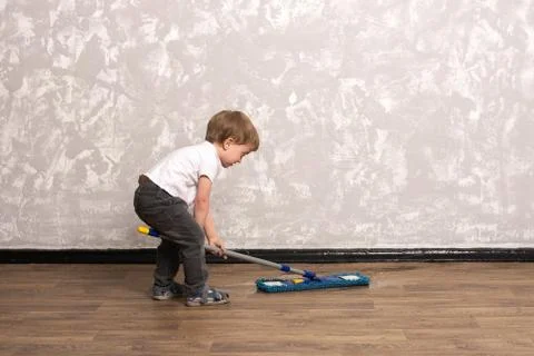 Three year old boy washes the floor in the apartment. Stock Photos