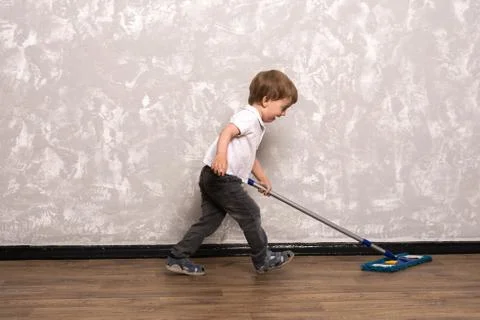Three year old boy washes the floor in the apartment. Stock Photos