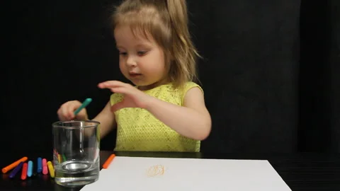 Three year old child draws with colored pencils and smiles in a yellow t-shirt Stock Footage 108056157