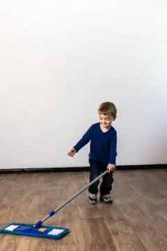 A three-year-old child mops the floor in the apartment. Stock Photos
