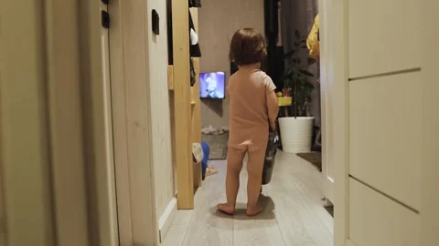 A three-year-old child vacuums at home, showing a love for cleanliness. The Stock Footage 311246878