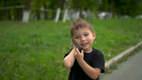 Three year old child walking in park talking on phone closeup. 4k Stock Footage 322518319