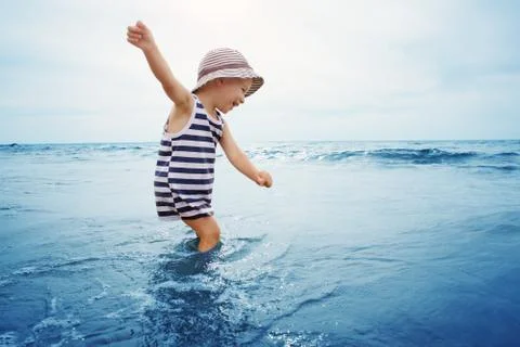 Three years old boy playing at the beach in the water Stock Photos