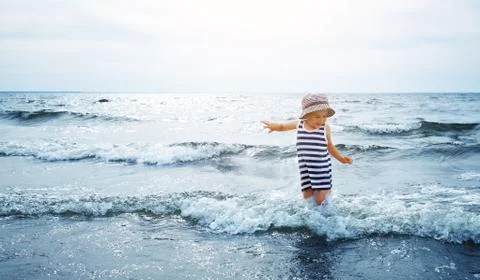 Three years old boy playing at the beach in the water Stock Photos