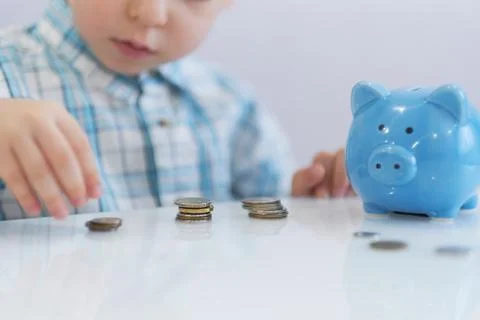 Three years old boy puts money in a piggy bank, piggybank concept. mantesori  Stock Photos