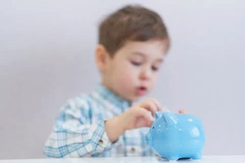 Three years old boy puts money in a piggy bank, piggybank concept. mantesori  Stock Photos