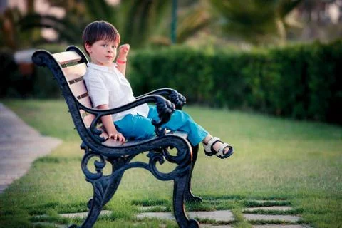 Three years old boy sitting on bench in park Stock Photos