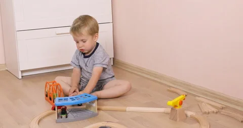 Three years old child boy play with wooden train, build toy railroad at home Stock Footage 96213307