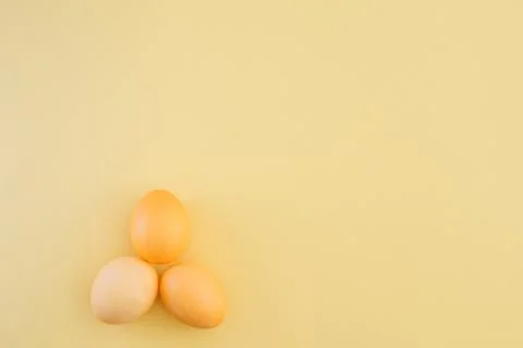 Three yellow colored easter eggs on trendy yellow background with place for text Fotos Stock