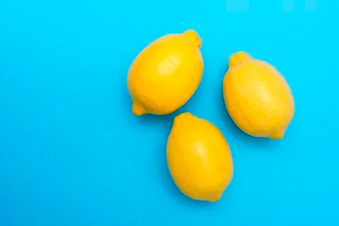 Three yellow lemons on a blue surface Stock Photos