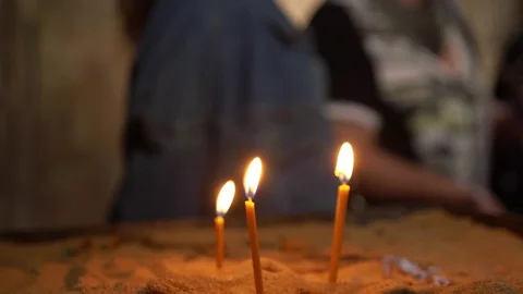 Three yellow lit candles stand in the sand. In the background - the people. Stock Footage 105680625