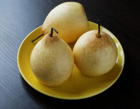 Three yellow pears on the plate on the table Stock Photos