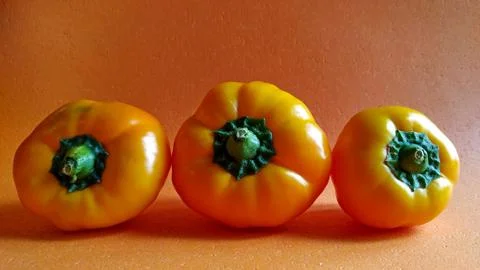 Three yellow pepper on an orange background. harvest time Stock Photos