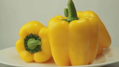 Three yellow sweet peppers on a light background, rotating Stock Footage 70952158