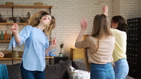 Three young active girlfriends dance disco and hop together, while having fun at Stock Footage 75668902