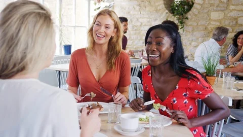 Three young adult women having brunch together and talking in a small Stock Footage