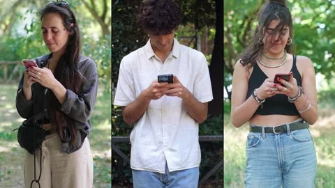Three young adults in collage, using smartphones for work, chat, and selfies Stock Footage 306320631