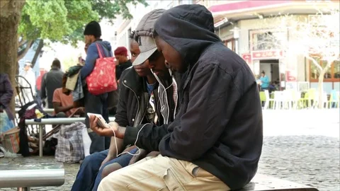 Three young African men sitting on bench sharing smart phone Stock Footage 80452045