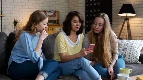 Three young and energetic best friend girls look over photos in telephone mobile Stockbeeldmateriaal 74994230
