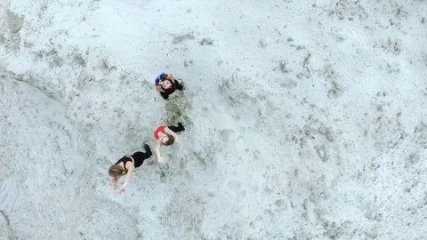 Three young, athletic women doing stretching exercises, warm-up, on the sandy Stock Footage