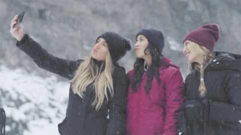 Three young beautiful ladies taking a selfie together on a snowy day Stock Footage 83620772