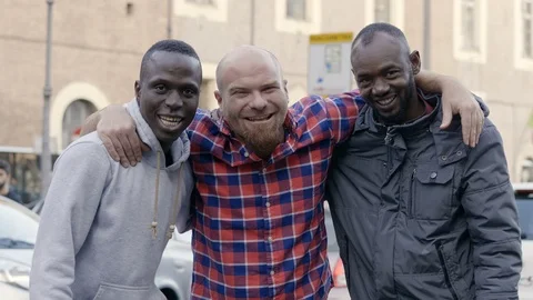 Three young black and white friends in the street smile at the camera Stock Footage 87336519