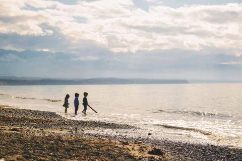 Three young children (2-3, 4-5) standing in silhouette on beach Stock Photos
