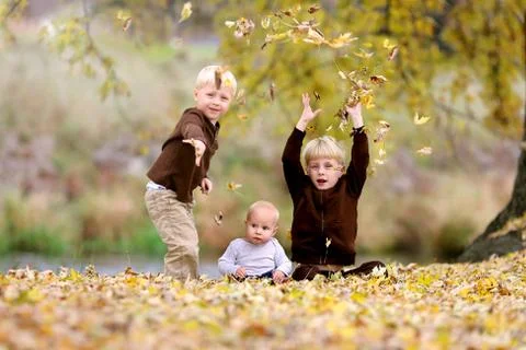 Three Young Children playing in Fallen Leaves Stock Photos