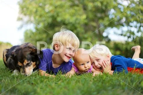 Three Young CHildren Relaxing Outside with Pet Dog Stock Photos