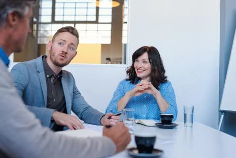 Three young colleagues talking strategy during an office meeting Stock Photos